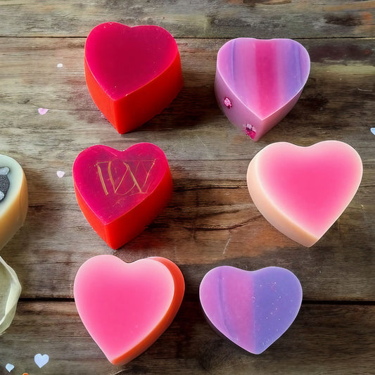 colorful soaps in heart shapes on wooden table